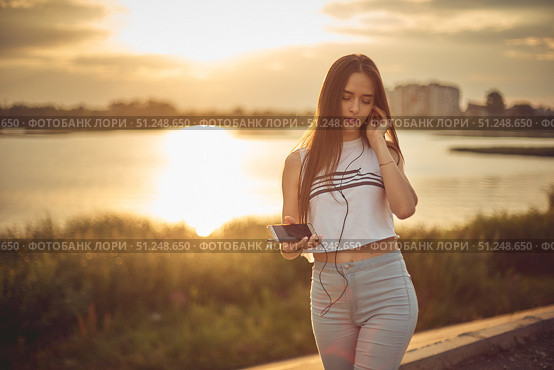 Young beautiful caucasian girl listening to music with smartphone walking in the city with headphones smiling - relax, youth, emancipation concept. Стоковое фото, фотограф Арзюков Вадим Николаевич / Фотобанк Лори