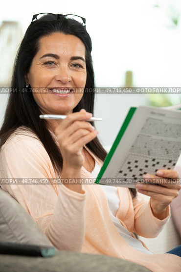 young beautiful woman doing crosswords in room. Стоковое фото, агентство Ingram Publishing / Фотобанк Лори