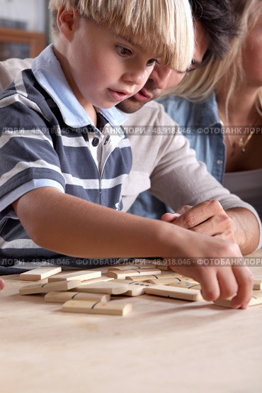 Young boy playing dominoes with his father. Стоковое фото, агентство Ingram Publishing / Фотобанк Лори