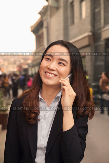 Young business woman on cell phone in Houhai, Beijing, China. Стоковое фото, агентство Ingram Publishing / Фотобанк Лори