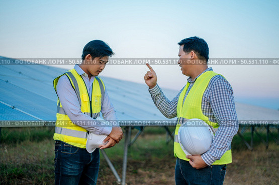 Young chief engineer is complain the trainee man on site of solar power plant, solar panel on background. Стоковое фото, агентство Ingram Publishing / Фотобанк Лори