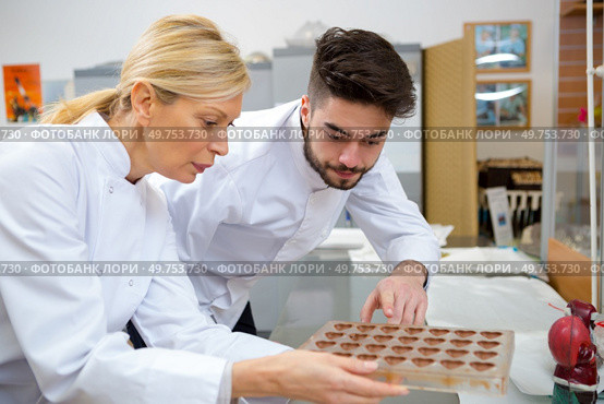 young chocolatier observing chocolates in the mold. Стоковое фото, агентство Ingram Publishing / Фотобанк Лори