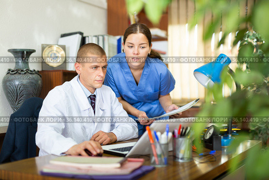 Young colleagues-doctors discuss the appointment of treatment, sitting at the computer in the office. Стоковое фото, фотограф Яков Филимонов / Фотобанк Лори