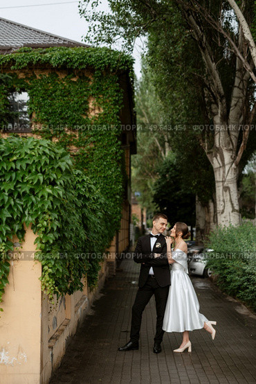 young couple bride and groom in a white short dress walking in the rain. Стоковое фото, агентство Ingram Publishing / Фотобанк Лори