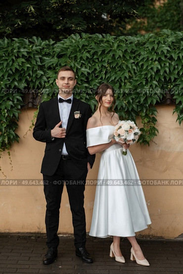 young couple bride and groom in a white short dress walking in the rain. Стоковое фото, агентство Ingram Publishing / Фотобанк Лори