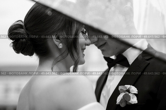 young couple bride and groom in a white short dress walking in the rain. Стоковое фото, агентство Ingram Publishing / Фотобанк Лори