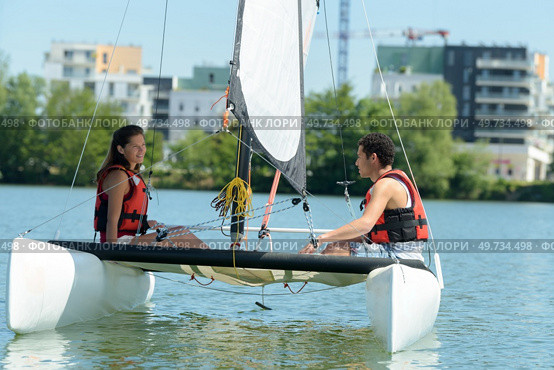 young couple on small catamaran sailboat. Стоковое фото, агентство Ingram Publishing / Фотобанк Лори