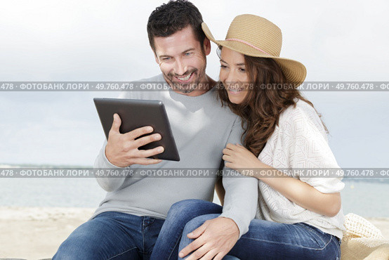 young couple using a digital tablet at seaside town. Стоковое фото, агентство Ingram Publishing / Фотобанк Лори