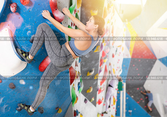 Young female alpinist practicing indoor rock-climbing on artificial boulder without safety belts. Стоковое фото, фотограф Яков Филимонов / Фотобанк Лори