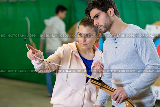 young female archer teaching a new member. Стоковое фото, агентство Ingram Publishing / Фотобанк Лори