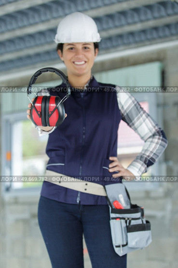 young female builder in  helmet showing earmuff. Стоковое фото, агентство Ingram Publishing / Фотобанк Лори
