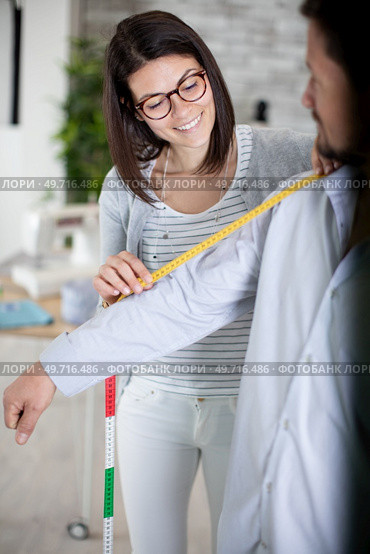 young female fashion designer taking measurements of a man. Стоковое фото, агентство Ingram Publishing / Фотобанк Лори