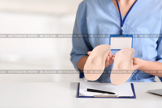 Young female nurse holding orthopedic insoles in clinic, closeup. Стоковое фото, фотограф Pixel_shot / Фотобанк Лори
