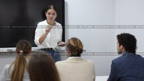 Young female teacher giving lecture to group of student Young female professor explaining subject to classroom full of students Young female tutor teaching students in college. Стоковое видео, видеограф Яков Филимонов / Фотобанк Лори
