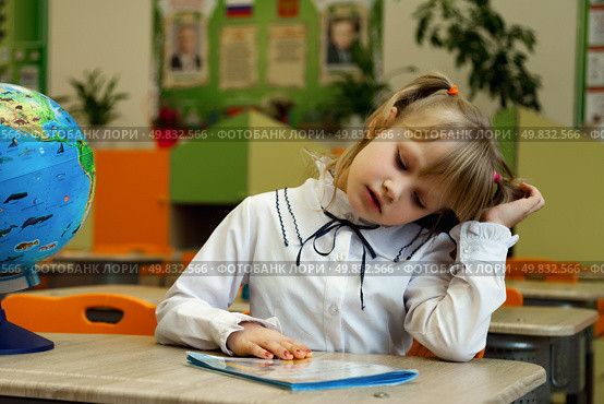 Young First-Grader Engaged in Reading Activity With Curiosity in a Colorful Classroom Setting. Стоковое фото, фотограф Aleksandr Golubev / Фотобанк Лори