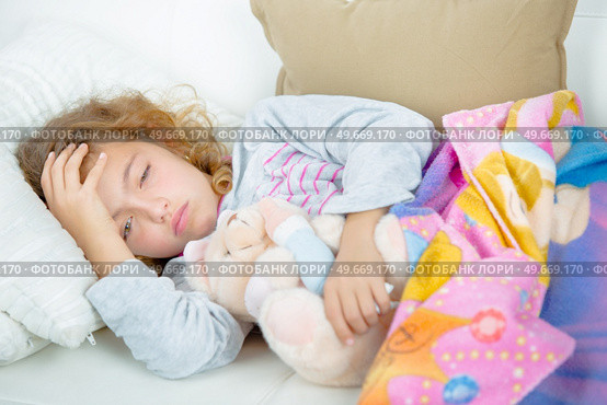 Young girl lying down holding head. Стоковое фото, агентство Ingram Publishing / Фотобанк Лори