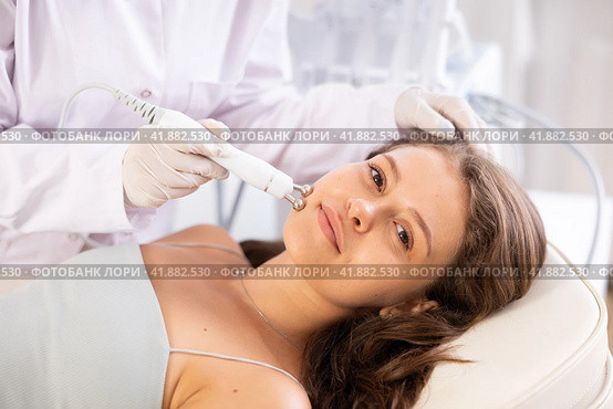 Young girl undergoing radiofrequency skin tightening procedure at cosmetology clinic. Стоковое фото, фотограф Яков Филимонов / Фотобанк Лори