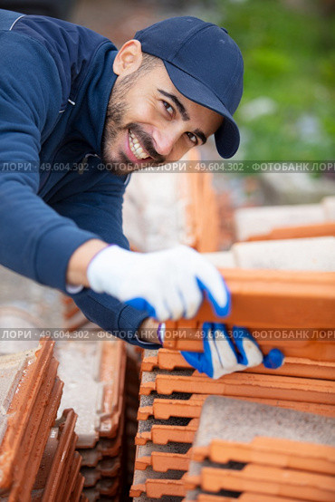 young happy brick layer at site. Стоковое фото, агентство Ingram Publishing / Фотобанк Лори
