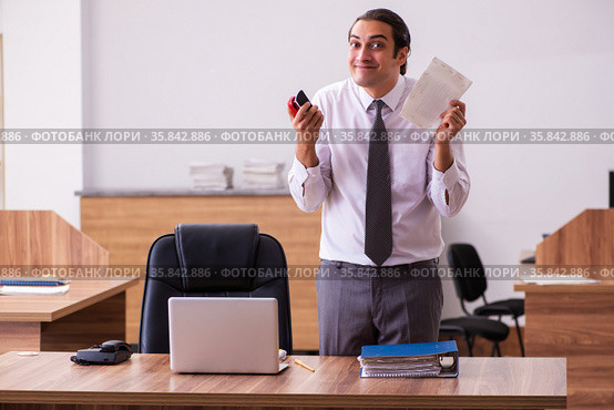 Young male employee stapling paper in the office. Стоковое фото, фотограф Elnur / Фотобанк Лори