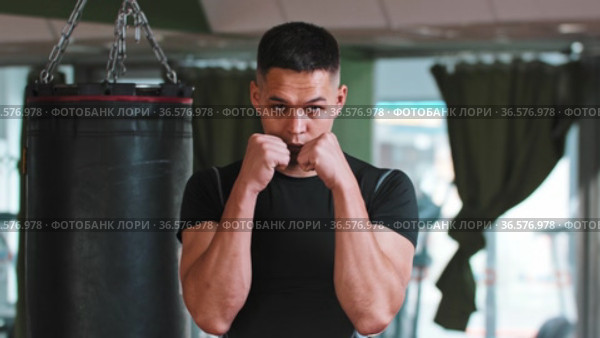 Young man boxer passing by the punching bag and stands in the protective stance. Стоковое видео, видеограф Константин Шишкин / Фотобанк Лори