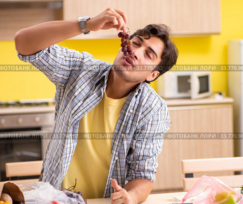 Young man calculating expences for vegetables in kitchen. Стоковое фото, фотограф Elnur / Фотобанк Лори