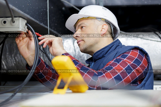 young man electrician wiring inside ceiling. Стоковое фото, агентство Ingram Publishing / Фотобанк Лори