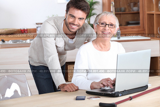 Young man helping senior woman with a laptop compute. Стоковое фото, агентство Ingram Publishing / Фотобанк Лори