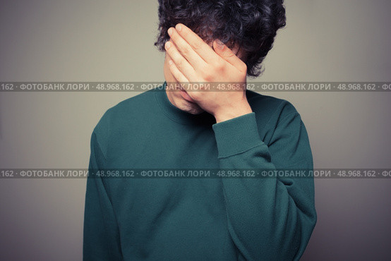 Young man is hiding his face in the palms of his hands. Стоковое фото, агентство Ingram Publishing / Фотобанк Лори
