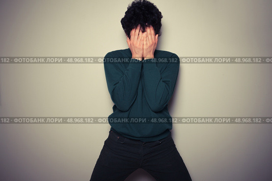 Young man is hiding his face in the palms of his hands. Стоковое фото, агентство Ingram Publishing / Фотобанк Лори