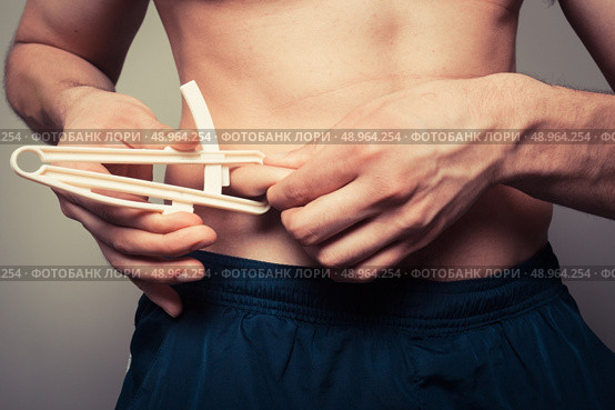 Young man is measuring his body fat with calipers. Стоковое фото, агентство Ingram Publishing / Фотобанк Лори