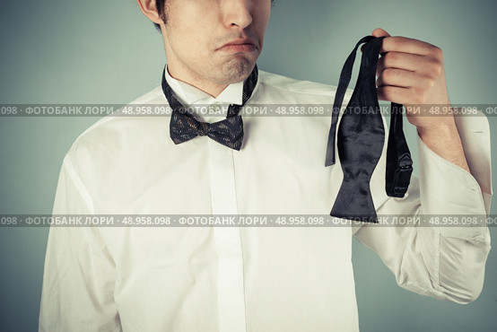 Young man is sad he couldn’t tie his own bow tie. Стоковое фото, агентство Ingram Publishing / Фотобанк Лори