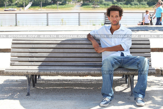 Young man sitting on a public bench. Стоковое фото, агентство Ingram Publishing / Фотобанк Лори