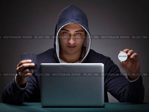 Young man wearing a hoodie sitting in front of a laptop computer. Стоковое фото, фотограф Elnur / Фотобанк Лори