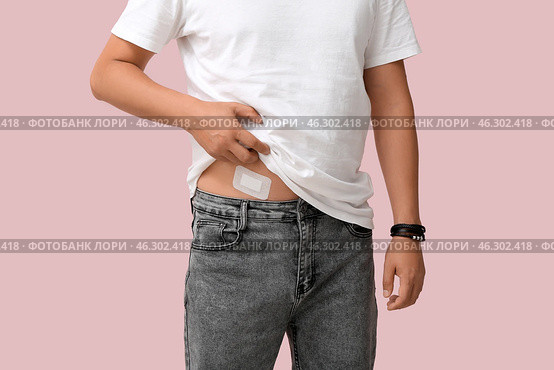 Young man with medical patch after appendix surgery on pink background, closeup. Стоковое фото, фотограф Pixel_shot / Фотобанк Лори