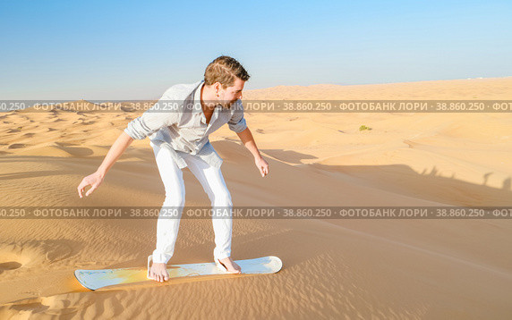 Young men sand surfing at the sand dunes of Dubai United Arab Emirates. Стоковое фото, фотограф Fokke Baarssen / Фотобанк Лори