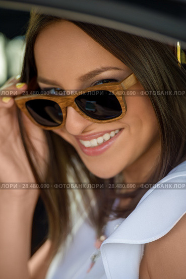Young pretty girl wearing sunglasses listening music with headphones in car. Summer fun. Стоковое фото, фотограф Kirill Kedrinskiy / Ingram Publishing / Фотобанк Лори