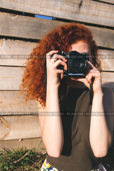 Young redhead photographer woman enjoying her passion outdoors. Стоковое фото, агентство Ingram Publishing / Фотобанк Лори