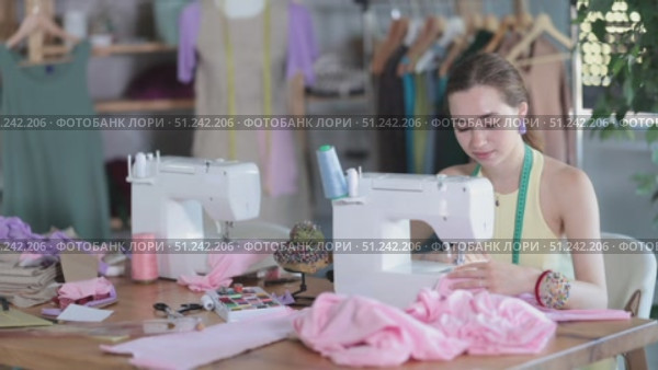 Young seamstress working on modern sewing machine in sewing workshop. Стоковое видео, видеограф Яков Филимонов / Фотобанк Лори