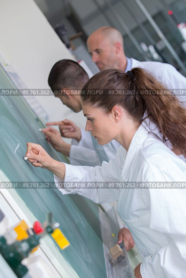 young students writing numbers on green chalk board in classroom. Стоковое фото, агентство Ingram Publishing / Фотобанк Лори