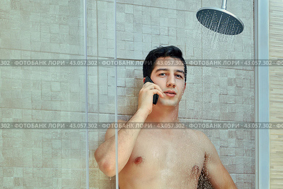 Young white man talks by smartphone in shower stall. Стоковое фото, фотограф Владимир Григорьев / Фотобанк Лори