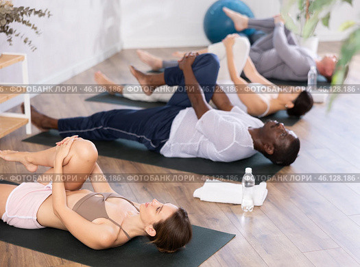 Young woman doing stretching Ardha Pawanmuktasana in yoga studio. Стоковое фото, фотограф Яков Филимонов / Фотобанк Лори
