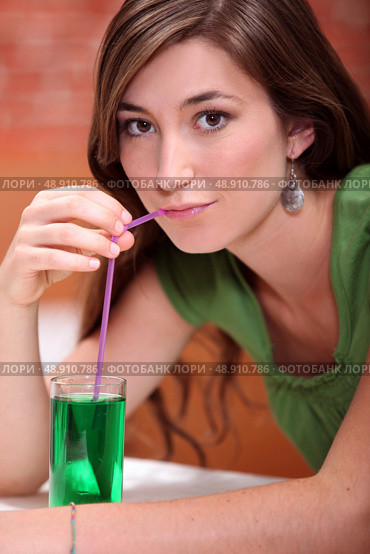 young woman dressed in green drinking a lemonade and mint cordial with a drinking straw. Стоковое фото, агентство Ingram Publishing / Фотобанк Лори