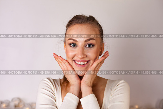 Young Woman Expresses Joy and Excitement in a Bright Studio Setting With a Neutral Backdrop. Стоковое фото, фотограф Aleksandr Golubev / Фотобанк Лори