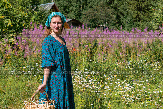 Young woman in folk peasant clothes on the background of a blooming meadow and rural buildings. Стоковое фото, фотограф Евгений Харитонов / Фотобанк Лори