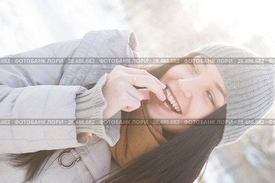 Young woman in winter outfit eats a biscuit lit by sunshine. Стоковое фото, фотограф Kirill Kedrinskiy / Ingram Publishing / Фотобанк Лори