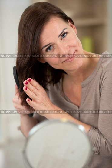 young woman is combing her hair. Стоковое фото, агентство Ingram Publishing / Фотобанк Лори