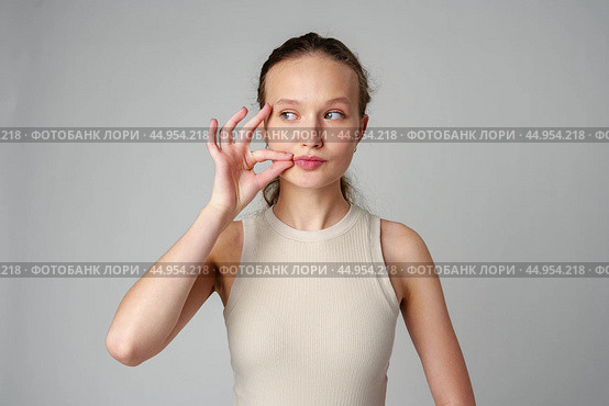 Young Woman Making a Hush Gesture on gray background in studio. Стоковое фото, фотограф Сергей Толмачёв / Фотобанк Лори
