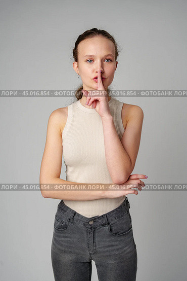 Young Woman Making a Hush Gesture on gray background in studio. Стоковое фото, фотограф Сергей Толмачёв / Фотобанк Лори