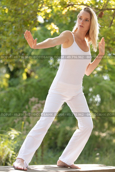 young woman praticing tai chi chuan outdoors in the sunshine. Стоковое фото, агентство Ingram Publishing / Фотобанк Лори