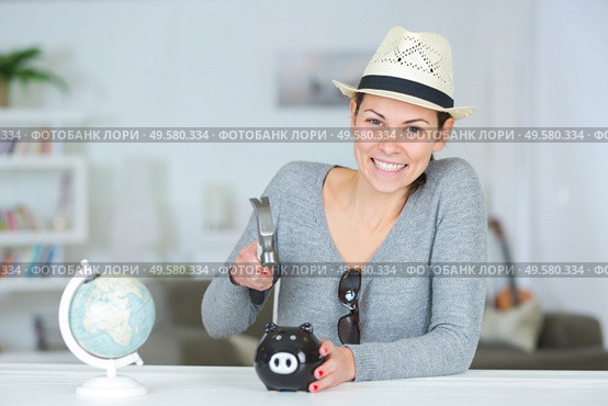 young woman smashing piggy bank with a hammer. Стоковое фото, агентство Ingram Publishing / Фотобанк Лори
